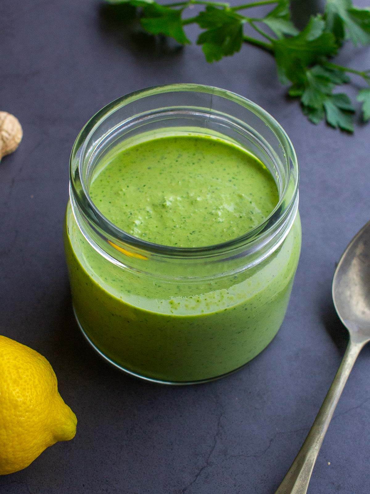 A jar of creamy vegan sauce with lemons and parsley, perfect for dressing salads, tossing with pasta, or using for falafel wraps.