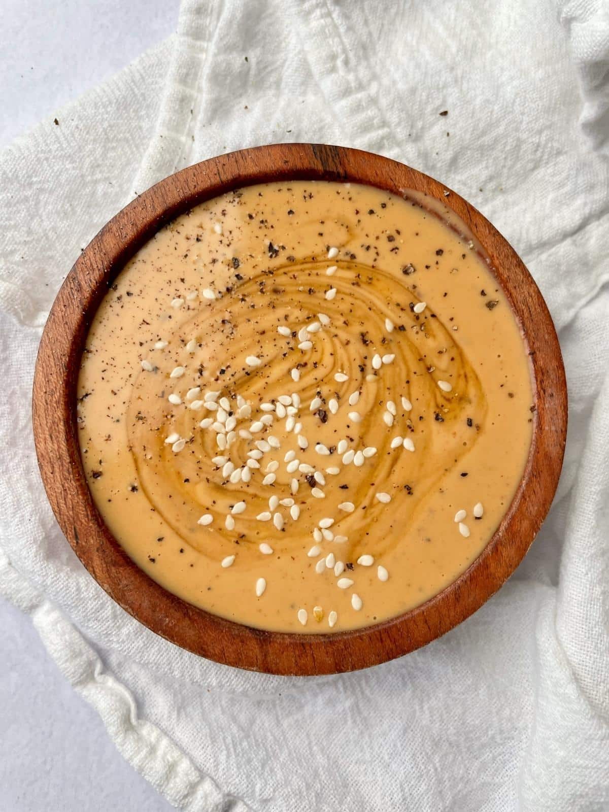 A creamy bowl of spicy Tahini sauce with sesame seeds on top.