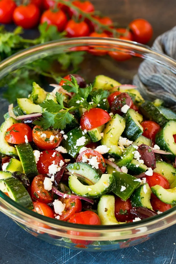 A bowl of Mediterranean salad with tomatoes, cucumbers, peppers and olives. / This Mediterranean salad is a blend of tomatoes, cucumbers, bell peppers, red onion, olives and feta, all tossed together in a homemade dressing.