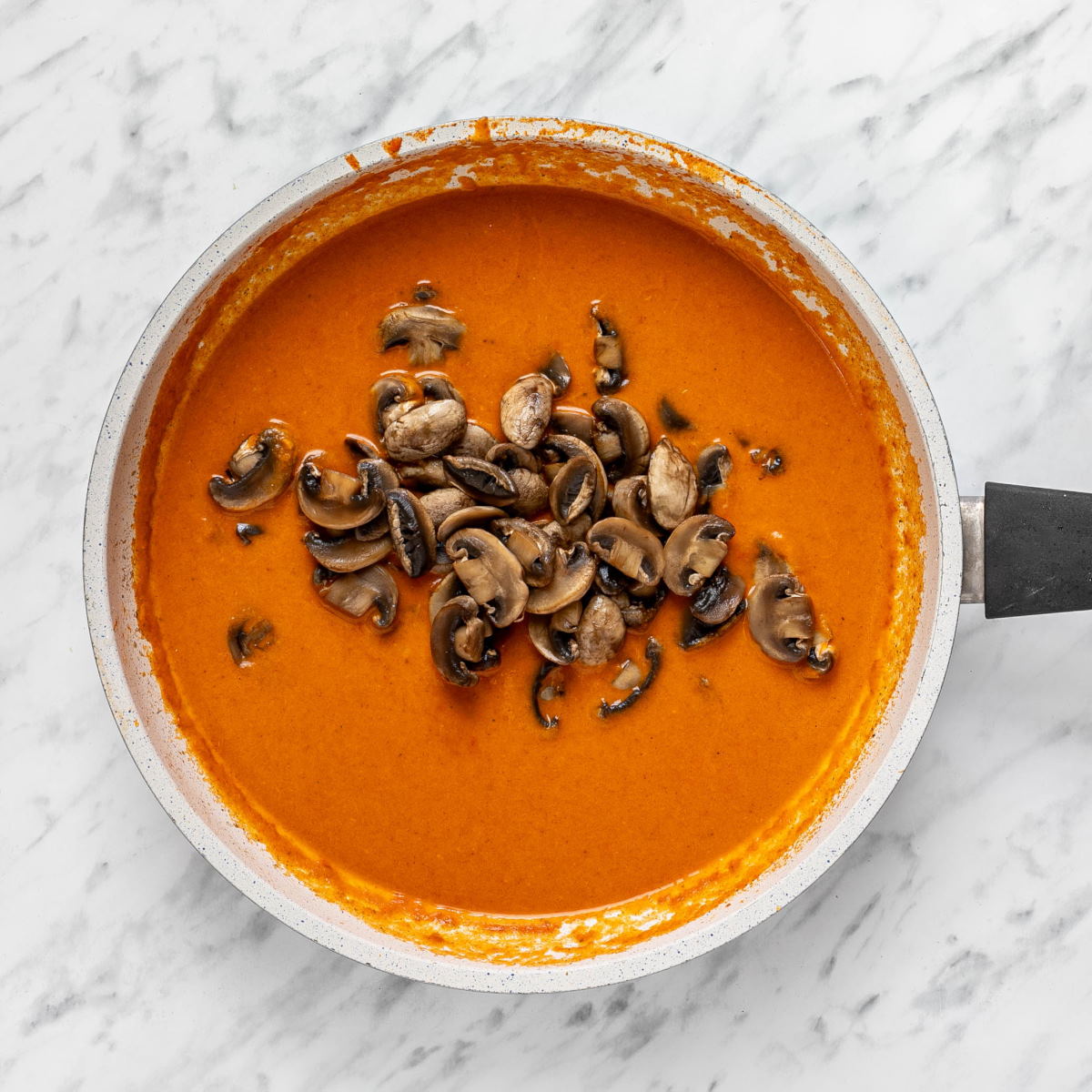 Thick and smooth Hungarian mushroom stew sauce with sauteed mushrooms on top in a pan.