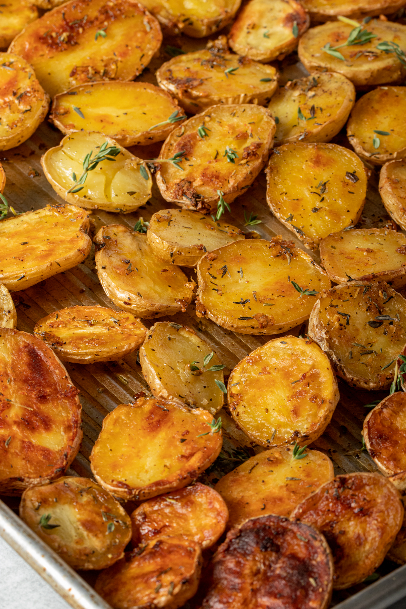 Close up shot of crispy roasted potatoes on a baking sheet.