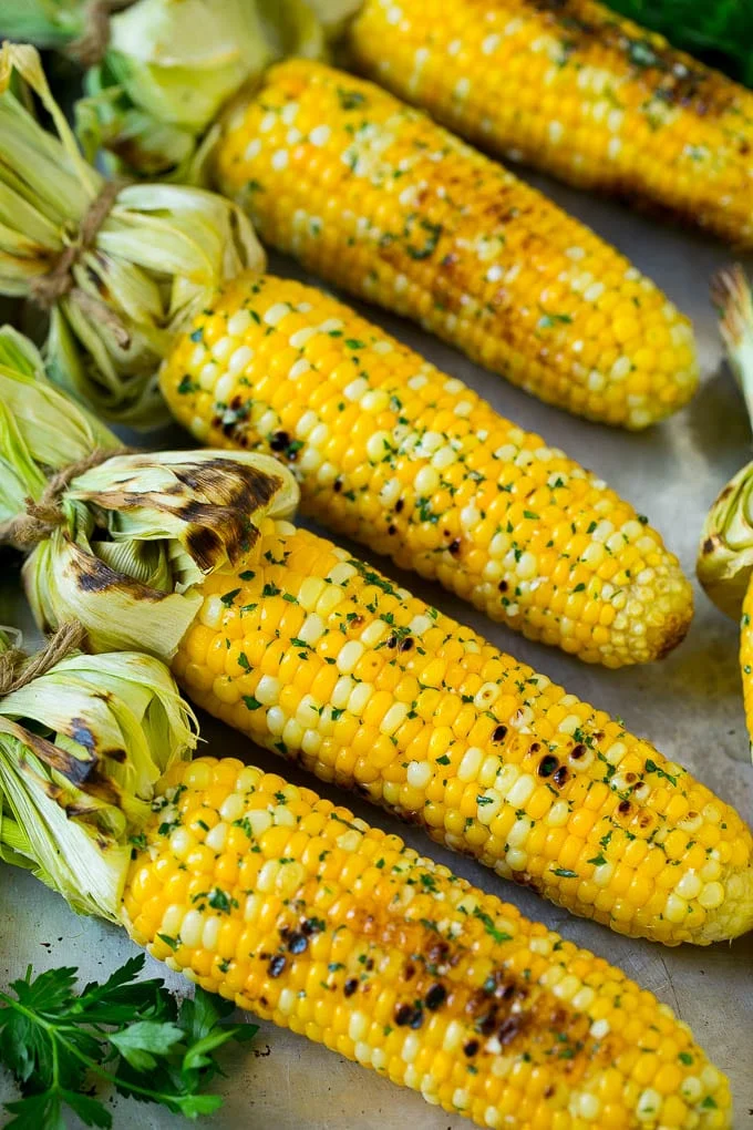Grilled corn on the cob topped with garlic and herb butter on a sheet pan. / Grilled Corn on the Cob Recipe | Corn Recipe #corn #grilling #summer #sidedish #dinner #dinneratthezoo
