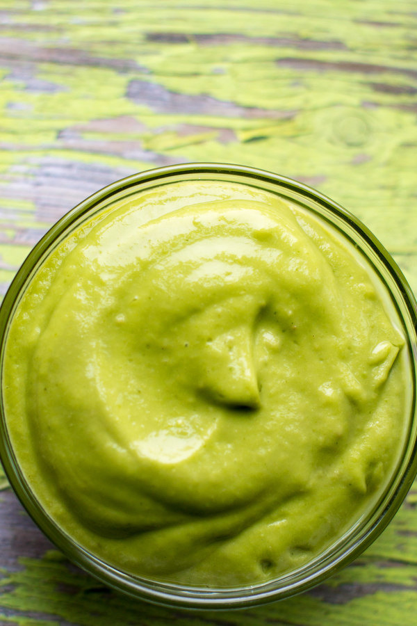 cilantro dipping sauce by intentionally eat in a glass bowl on a green painted board.
