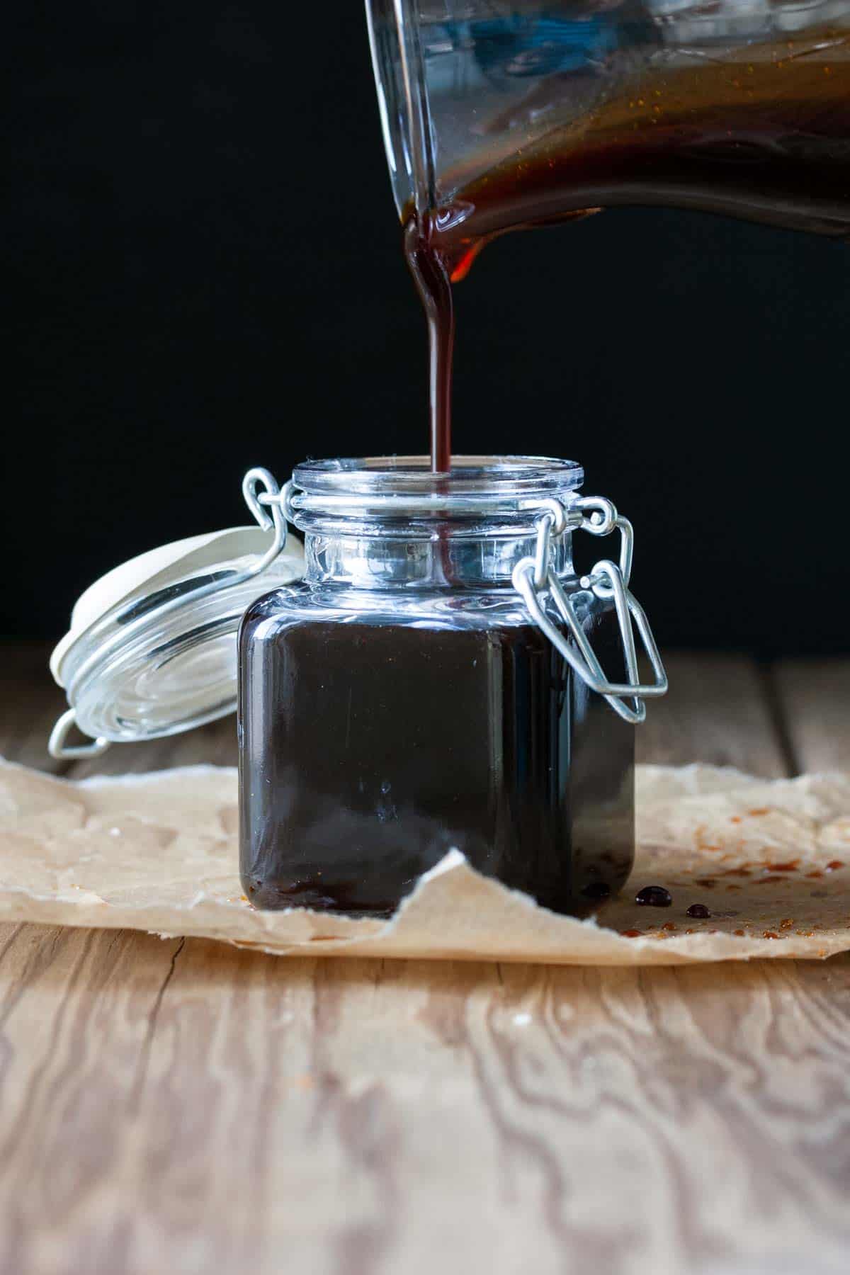 Glass jar filling with poured teriyaki sauce / This gluten-free vegan teriyaki sauce is sticky, sweet and so versatile. It's guaranteed to take any Asian inspired dish to a whole new flavor level! 