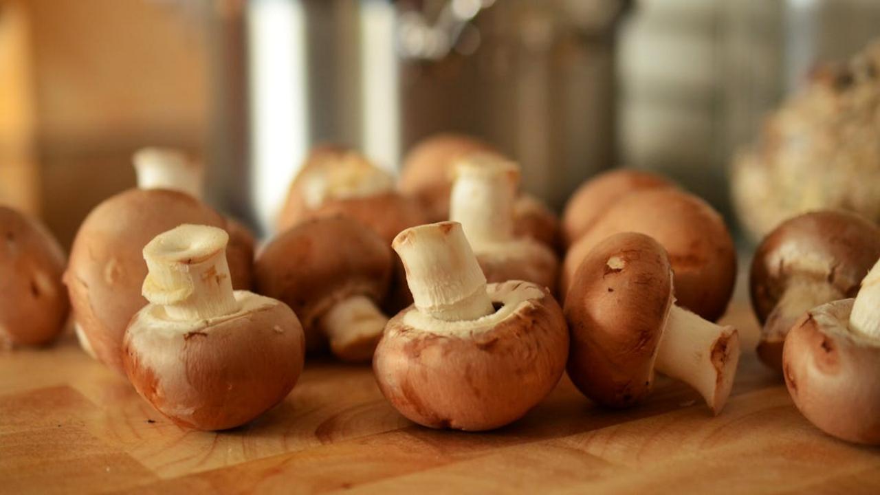 Close-up of fresh brown mushrooms on a wooden cutting board in a kitchen setting.